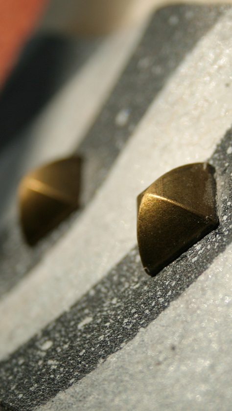 Macro photo of two pyramid studs on a paint spattered stripe belt.